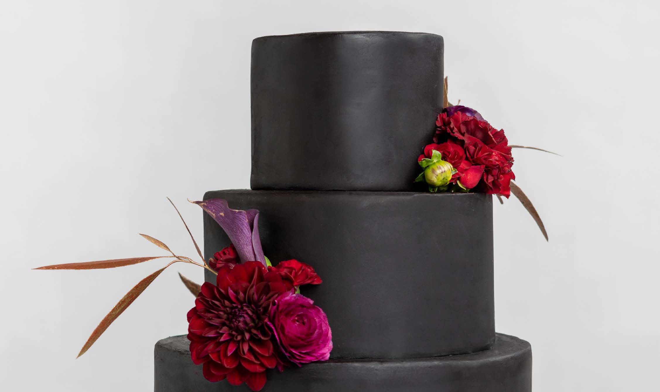 Black cake decorated with fresh red flowers