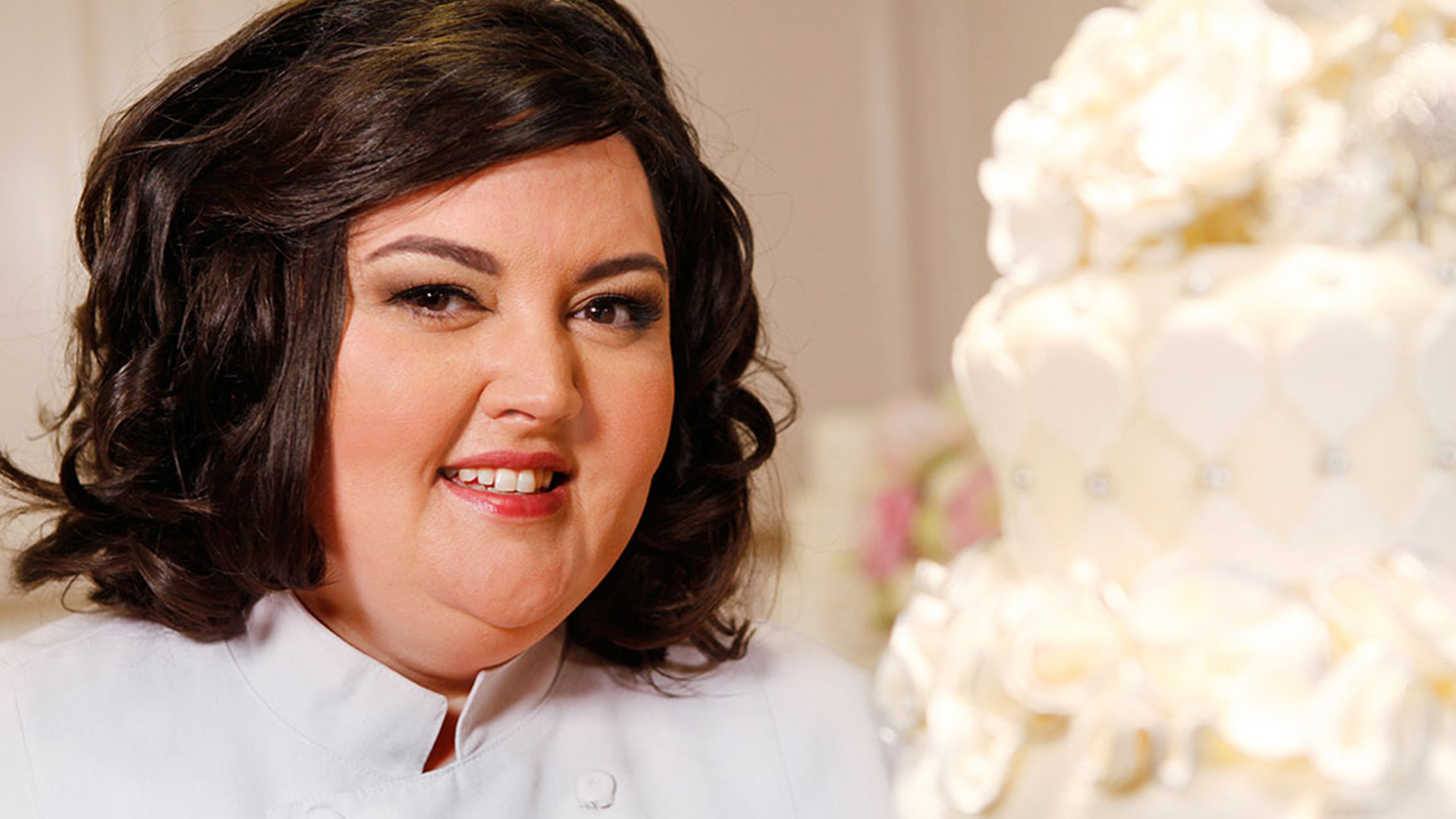 Headshot of a woman with a white flower cake
