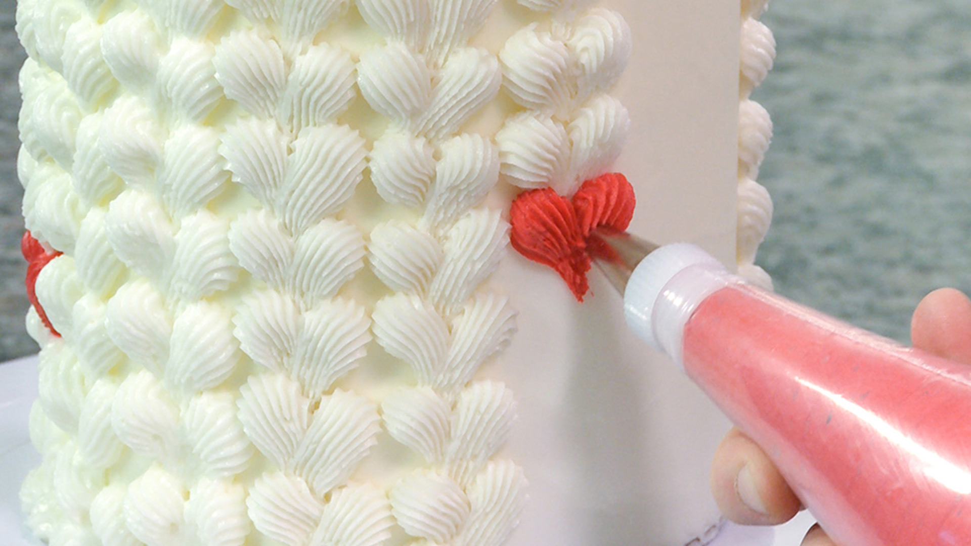 Piping buttercream hearts onto a cake